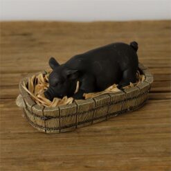 Picture a peaceful scene with a content little piglet nestled snugly in a basket, fast asleep. Its endearing presence adds a touch of warmth and whimsy to any room.